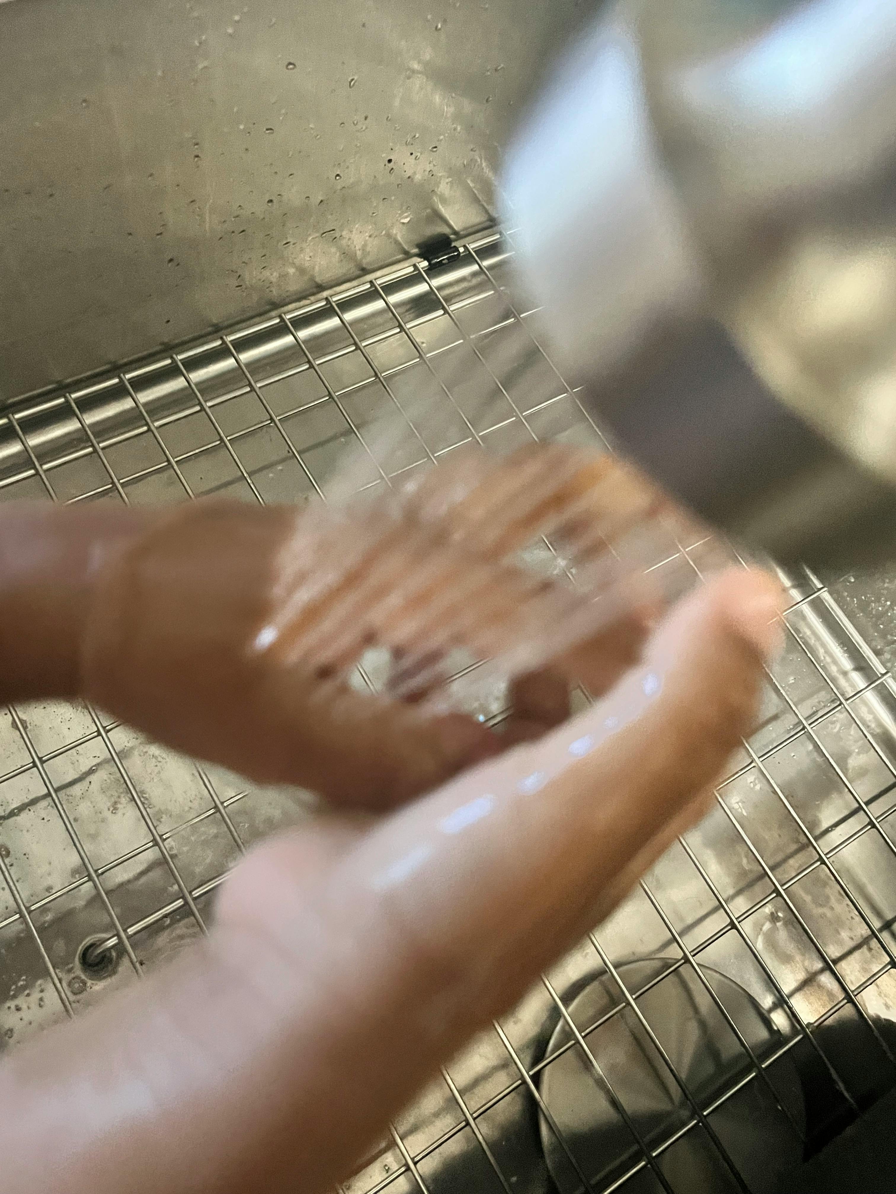 Person washing hands under running water in a sink