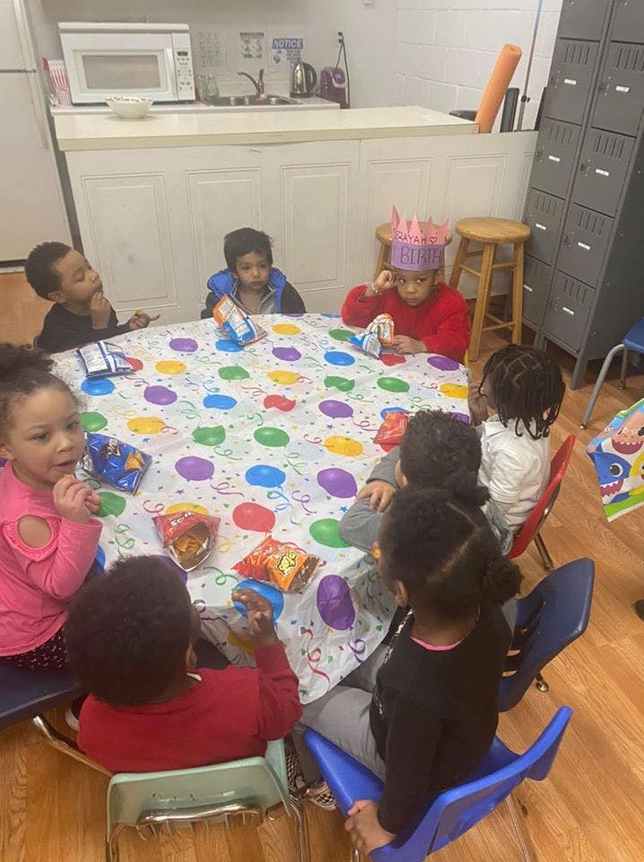 Children sitting around a table with a balloon-patterned tablecloth
