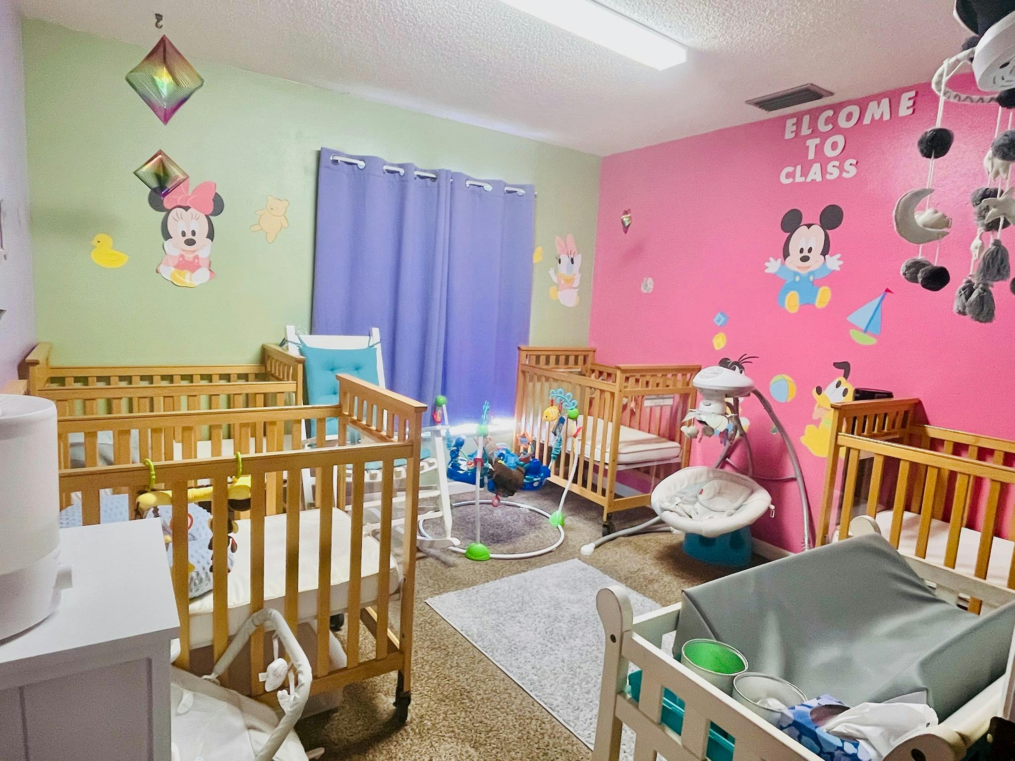 Nursery room with multiple wooden cribs and baby swings
