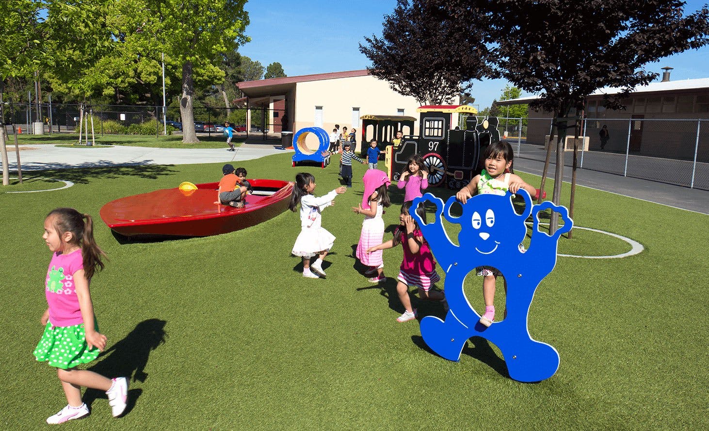 Children playing on a playground with a red boat and blue bear-shaped rocker