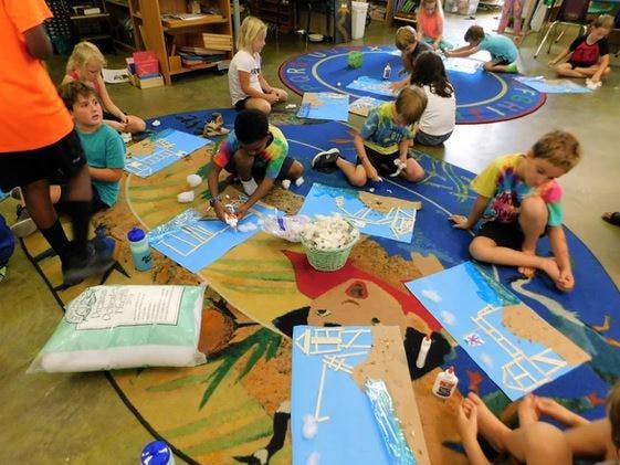 Children sitting on a rug doing art projects