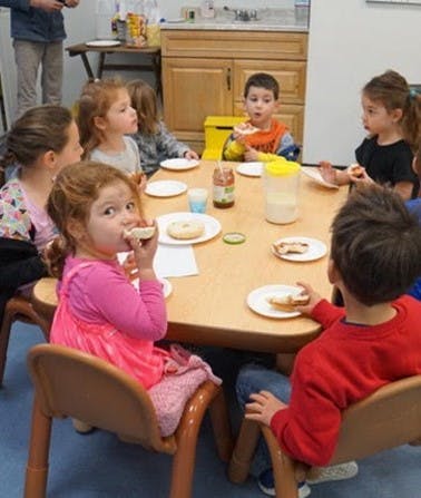 Children eating at a table in a classroom