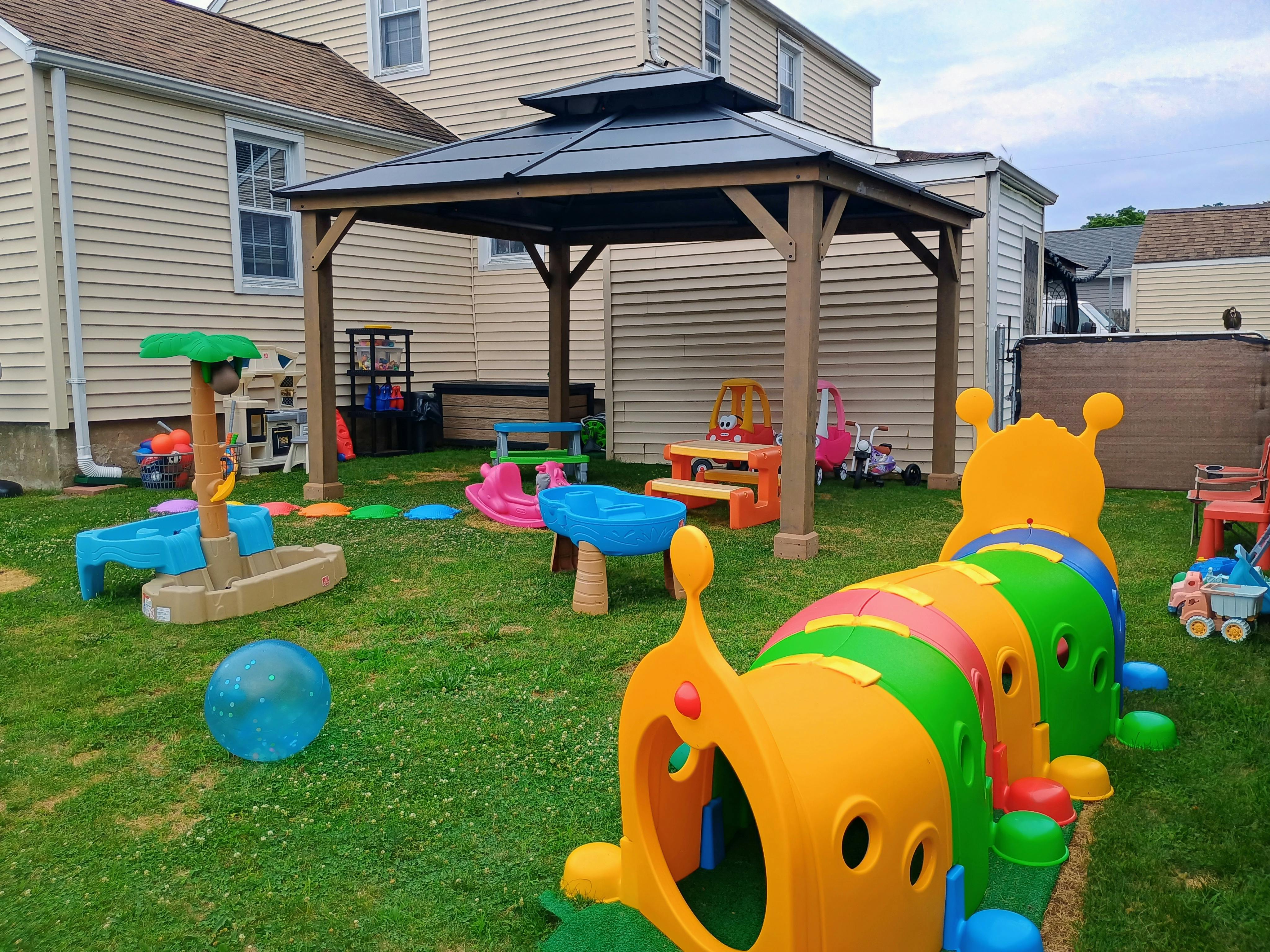 Plastic playground equipment and toys arranged in a residential backyard