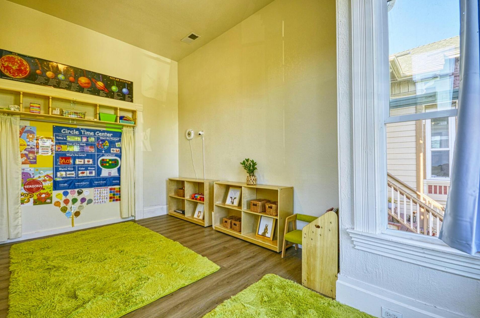 Classroom with green rugs, shelves, and educational posters