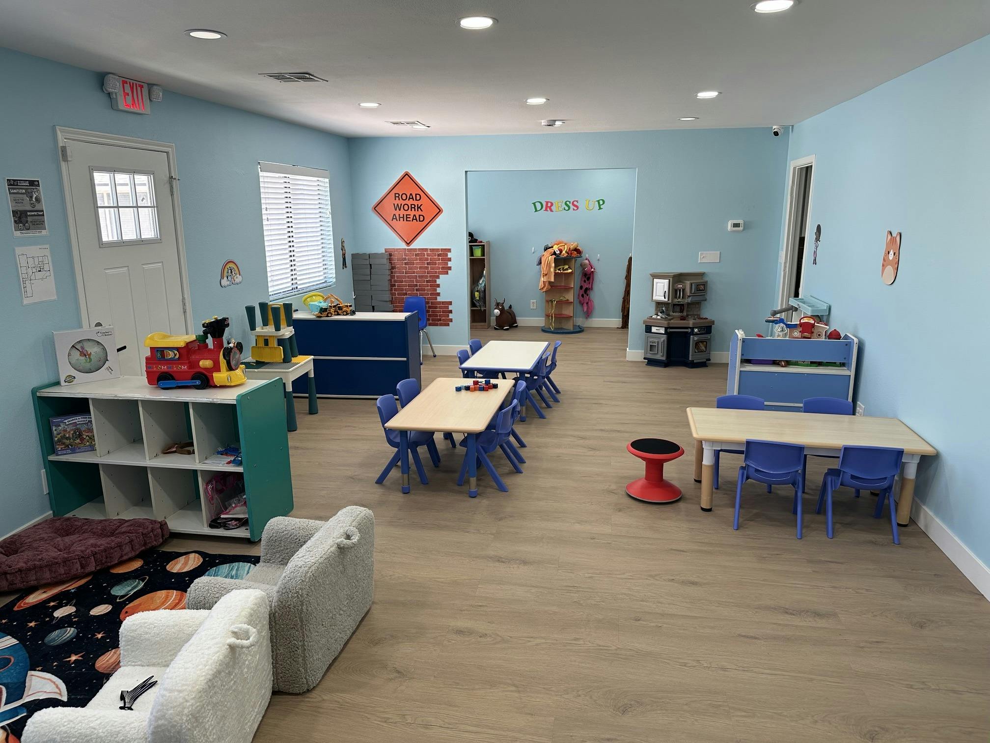 Childcare classroom with small tables chairs and toy stations