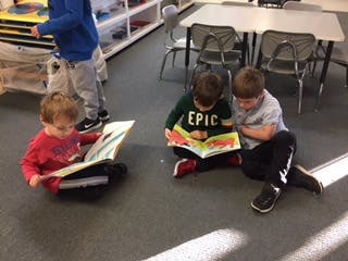 Three children sitting on the floor reading books