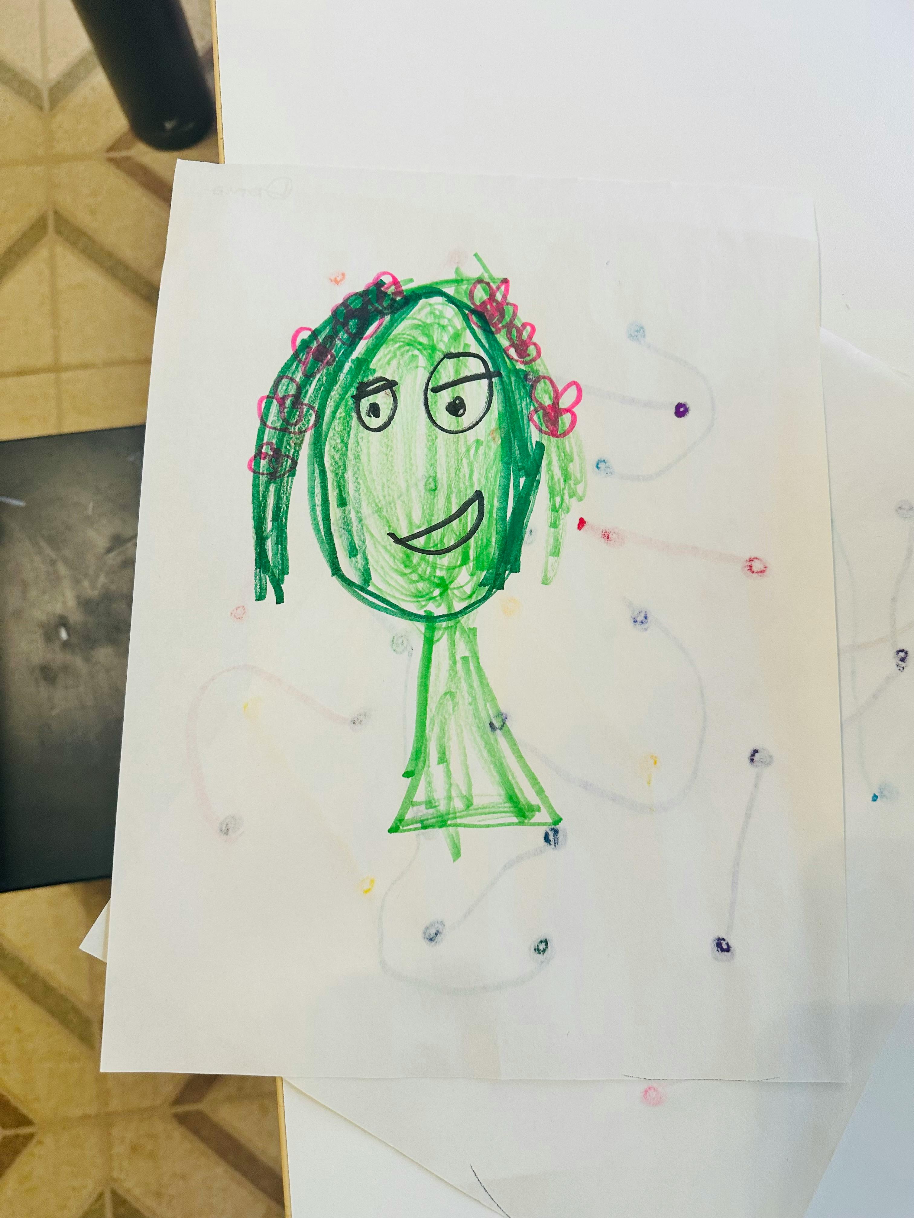 Child's drawing of a green-faced figure with pink flowers in its hair