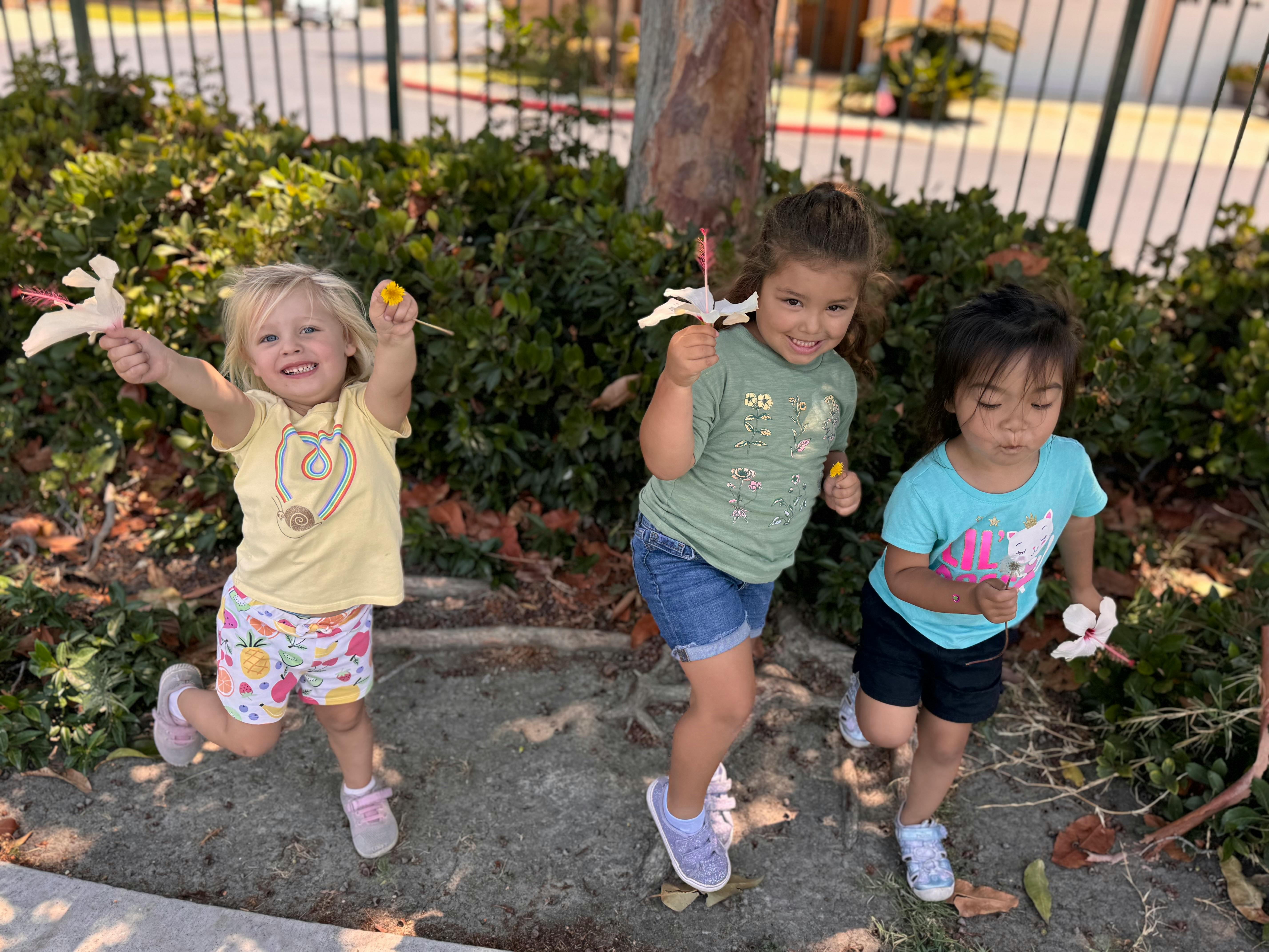 Three children holding flowers outdoors