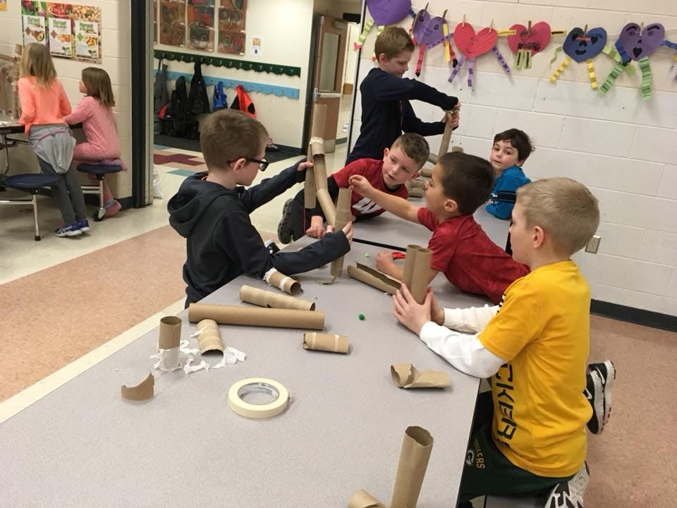 Children building with cardboard tubes and tape in a classroom