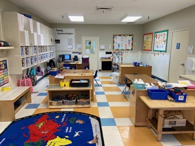 Classroom with cubbies, tables, computer, and a world map rug