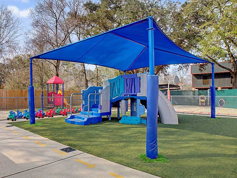 Playground with blue shade structure over a multi-level climbing set and slides