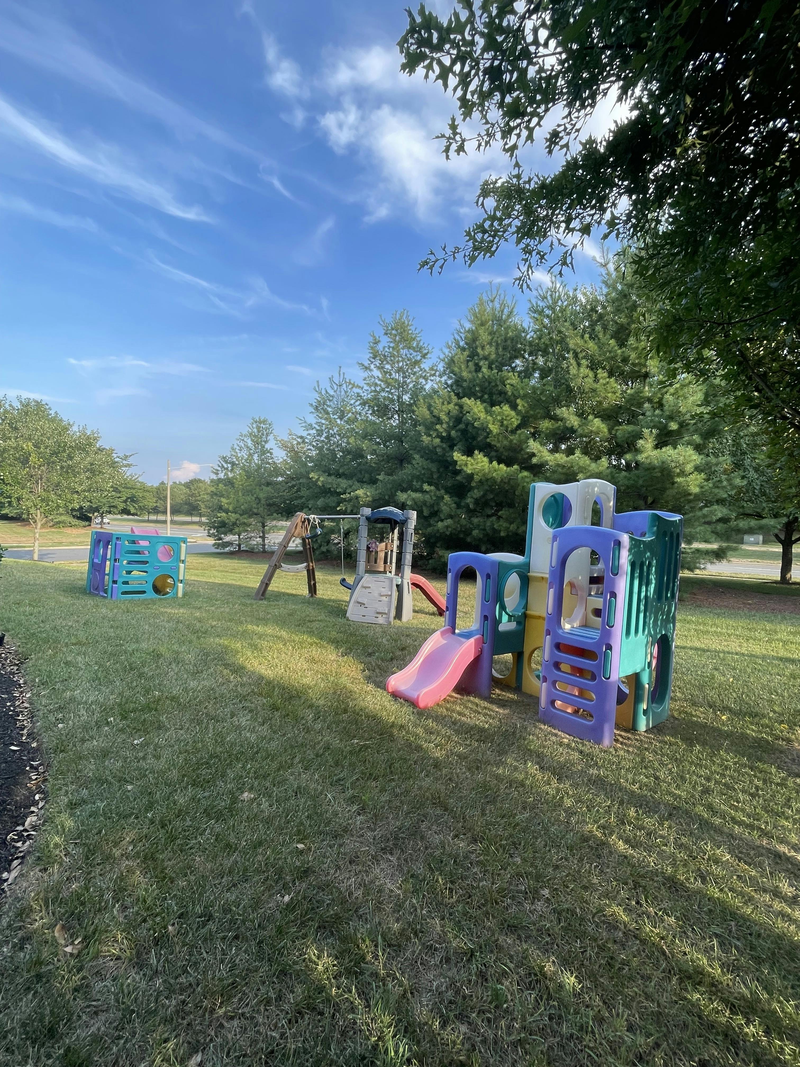 Outdoor playground with multiple colorful plastic play structures and swings