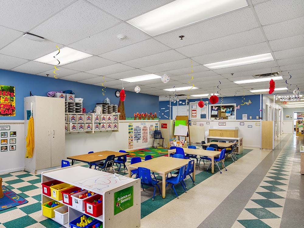Classroom with small tables and chairs, and play materials