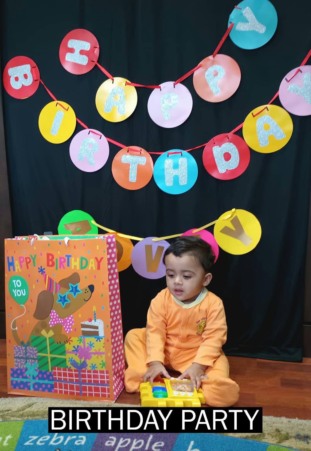 Child playing with a toy next to a gift bag and birthday banner