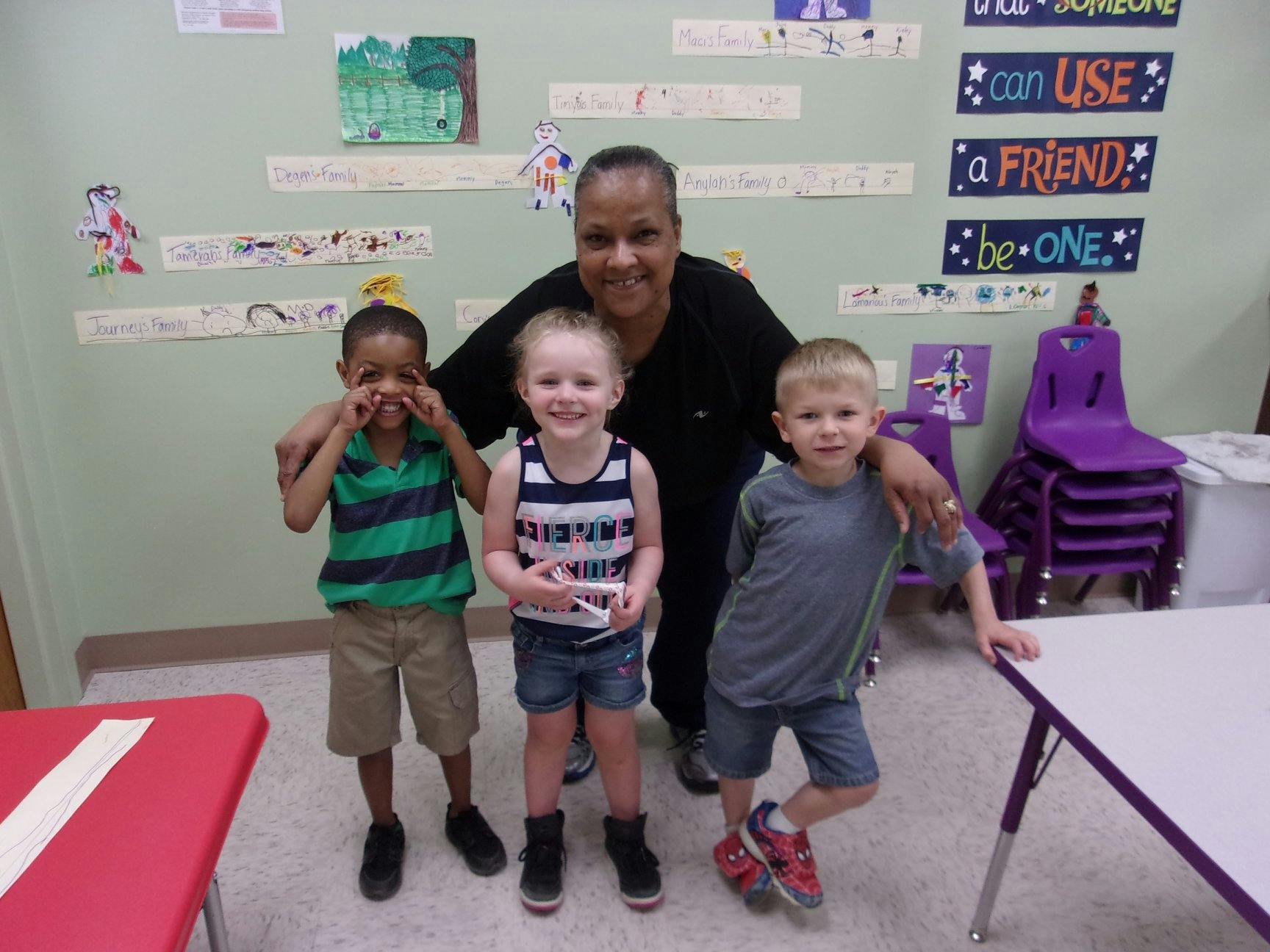 Adult and three children posing in a classroom
