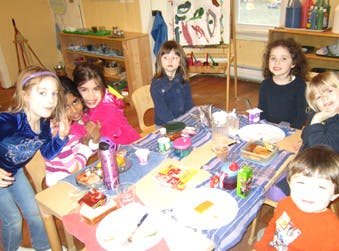 Six children sitting around a table with food