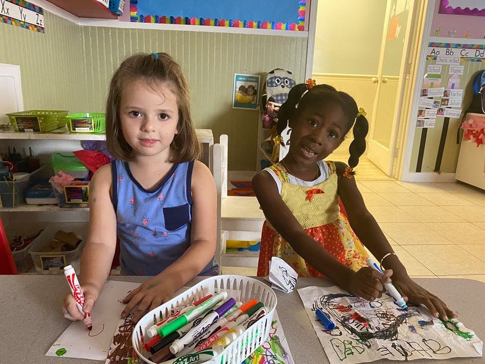 Two children drawing with markers at a table
