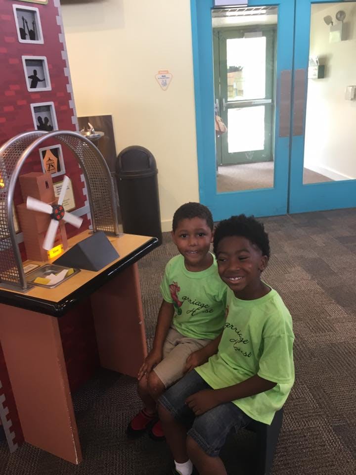 Two children sitting next to a science exhibit