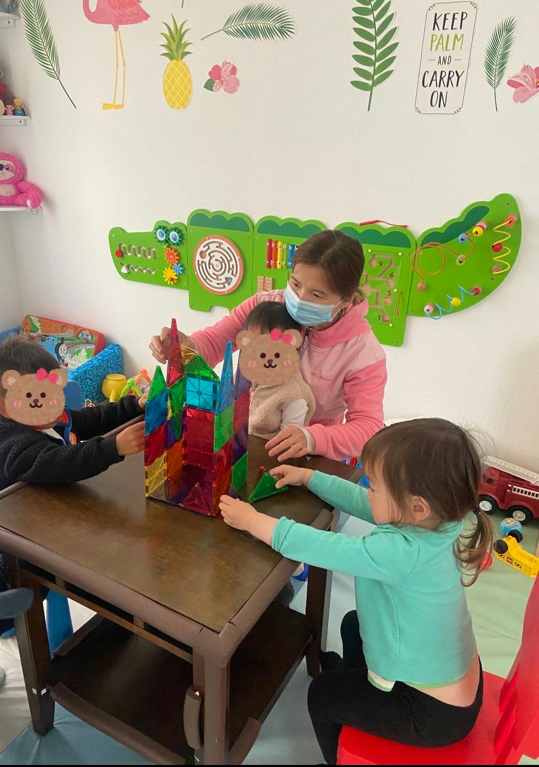 Adult and two children building with colorful magnetic blocks at a table