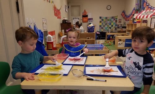 Three children painting at a table