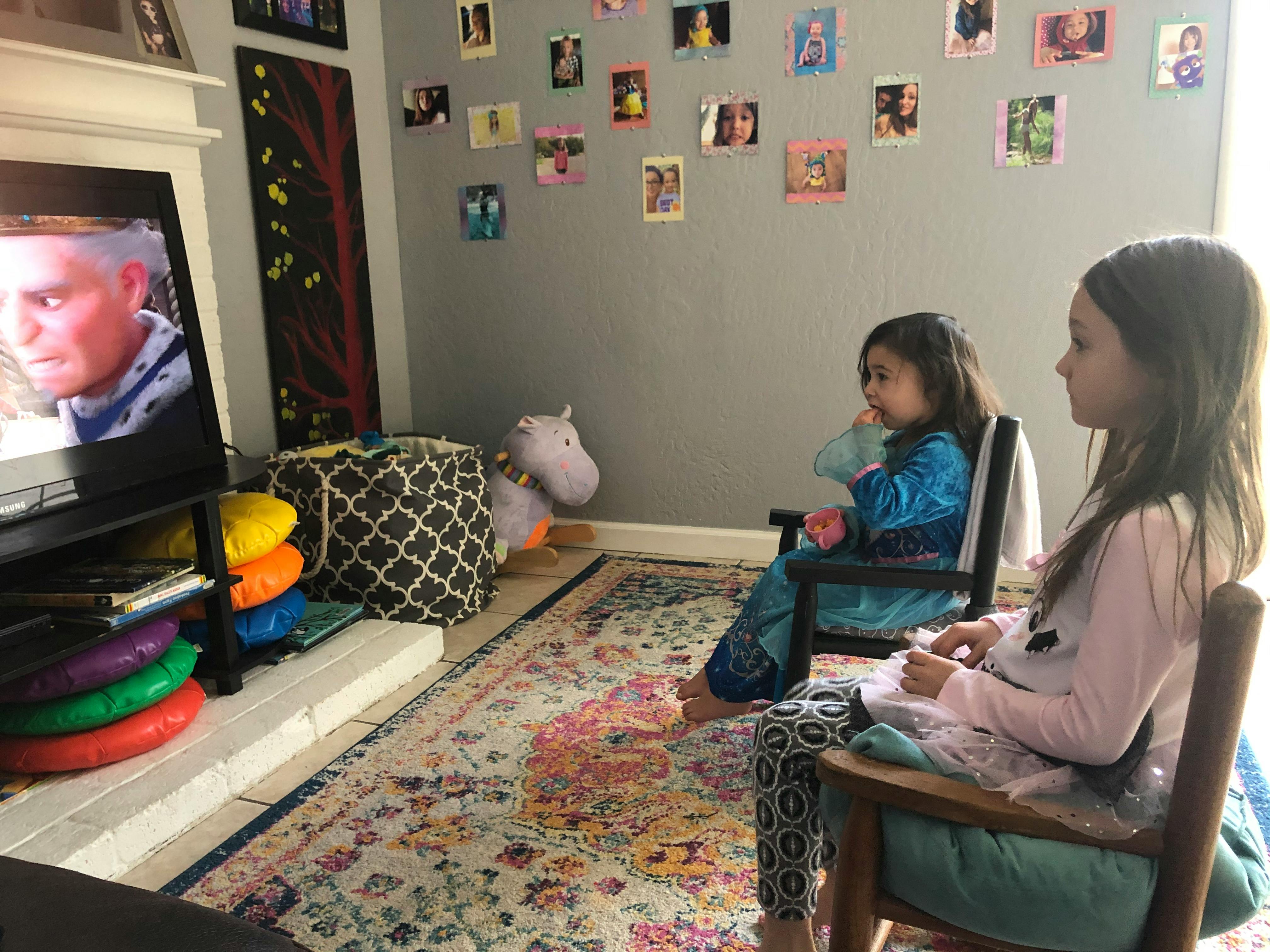 Two children sitting in chairs watching television