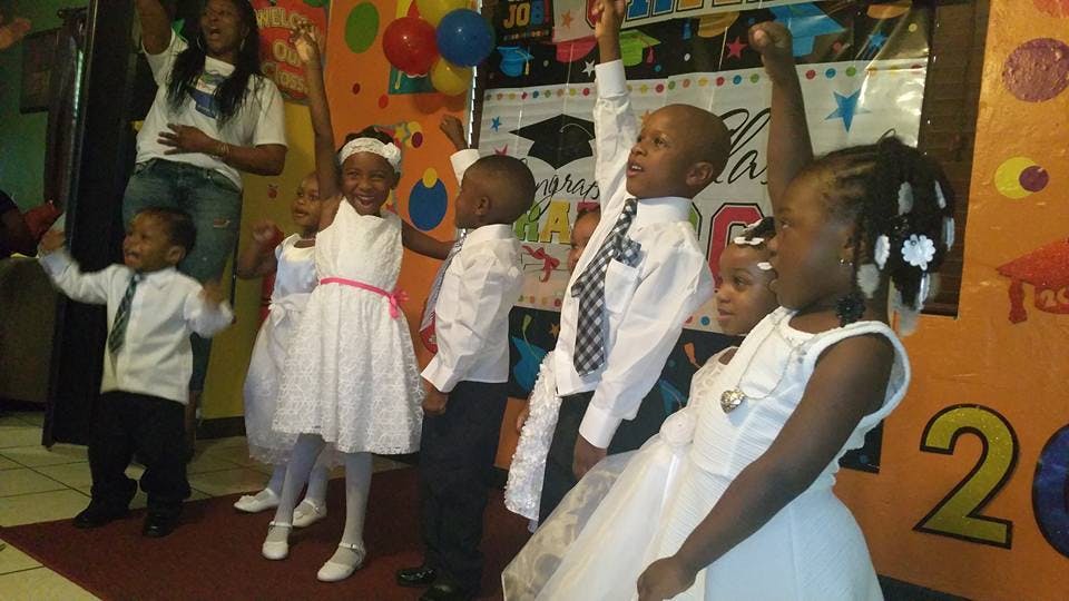 Children in white outfits raising their arms