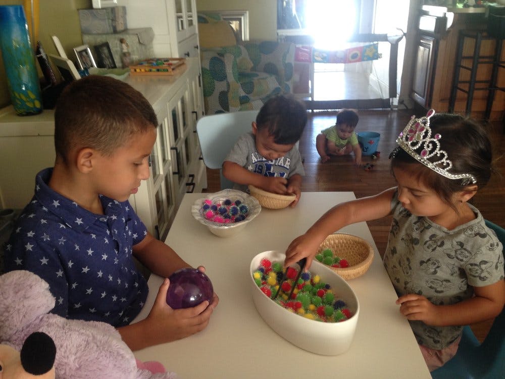 Children playing with colorful beads at a table