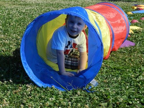 Child crawling through a colorful play tunnel