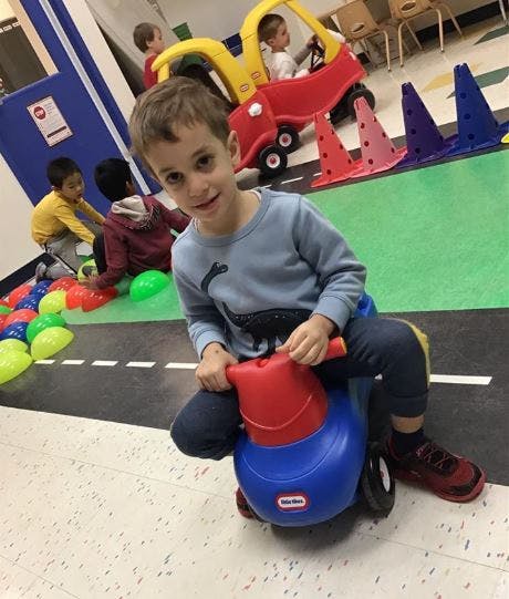 Child riding a toy car indoors