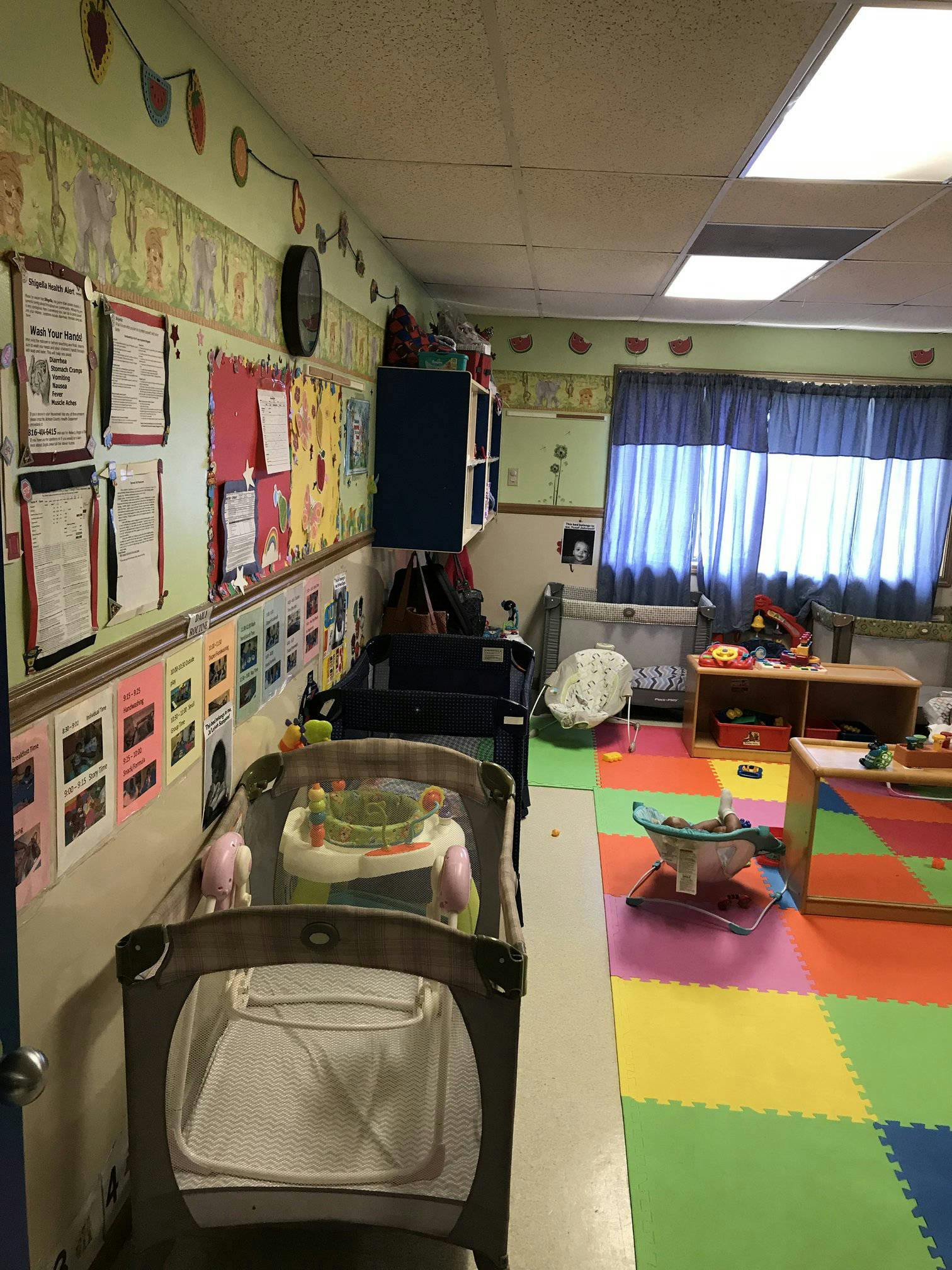 Nursery room with cribs, play mats, and wall decorations