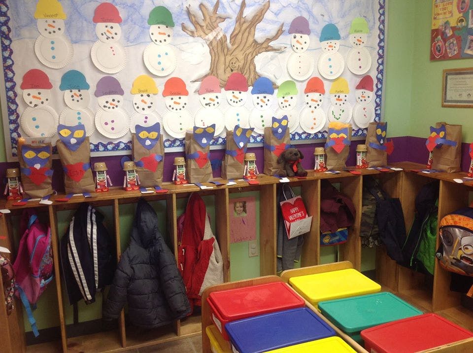 Classroom cubbies with coats and bags below a snowman and tree display