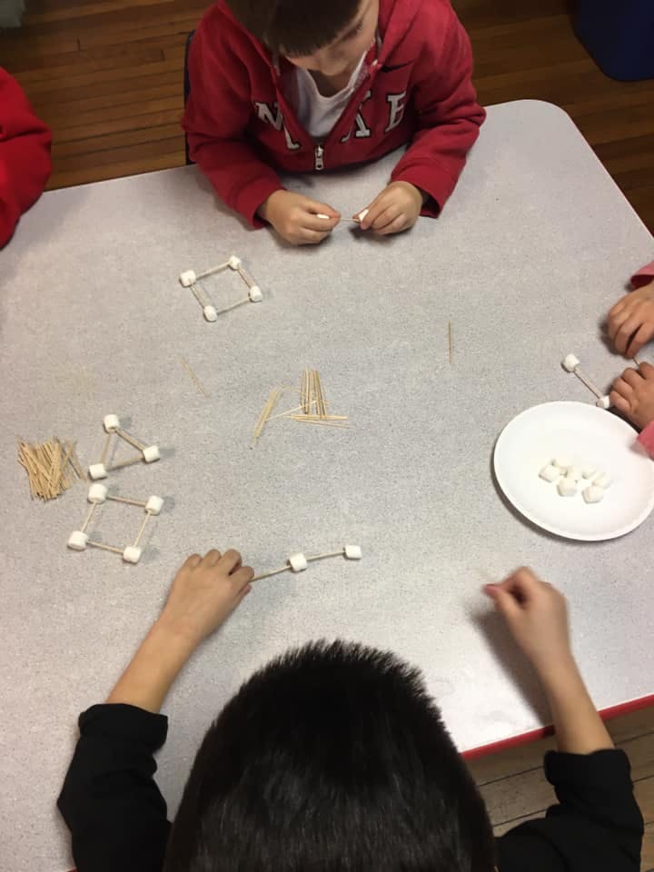 Children building structures with toothpicks and marshmallows at a table