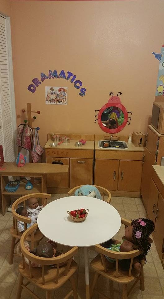 Playroom with a table and chairs, toy kitchen, and wall decor