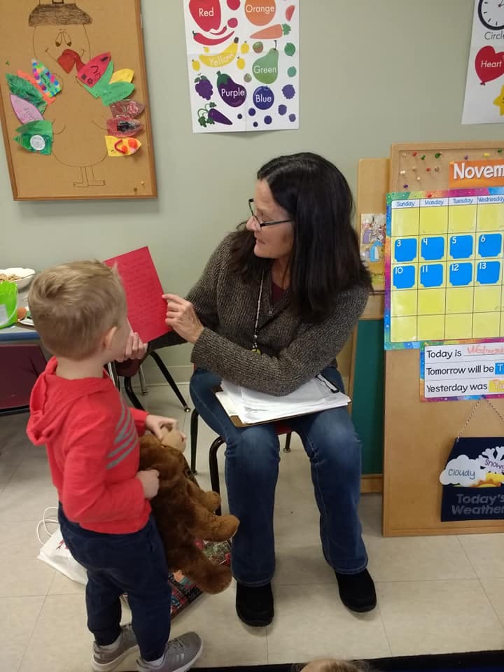 Person reading a book to a child in a classroom