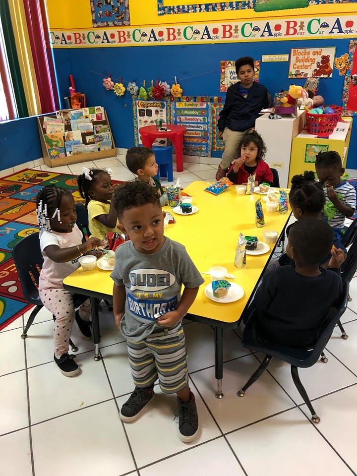Children sitting at a yellow table in a classroom