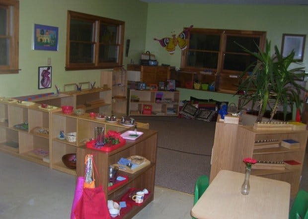 Classroom with wooden shelves, learning materials, and small tables