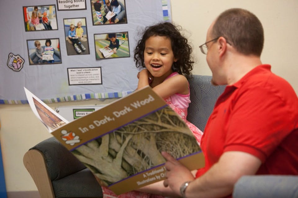 Adult and child reading a book titled "In a Dark, Dark Wood"