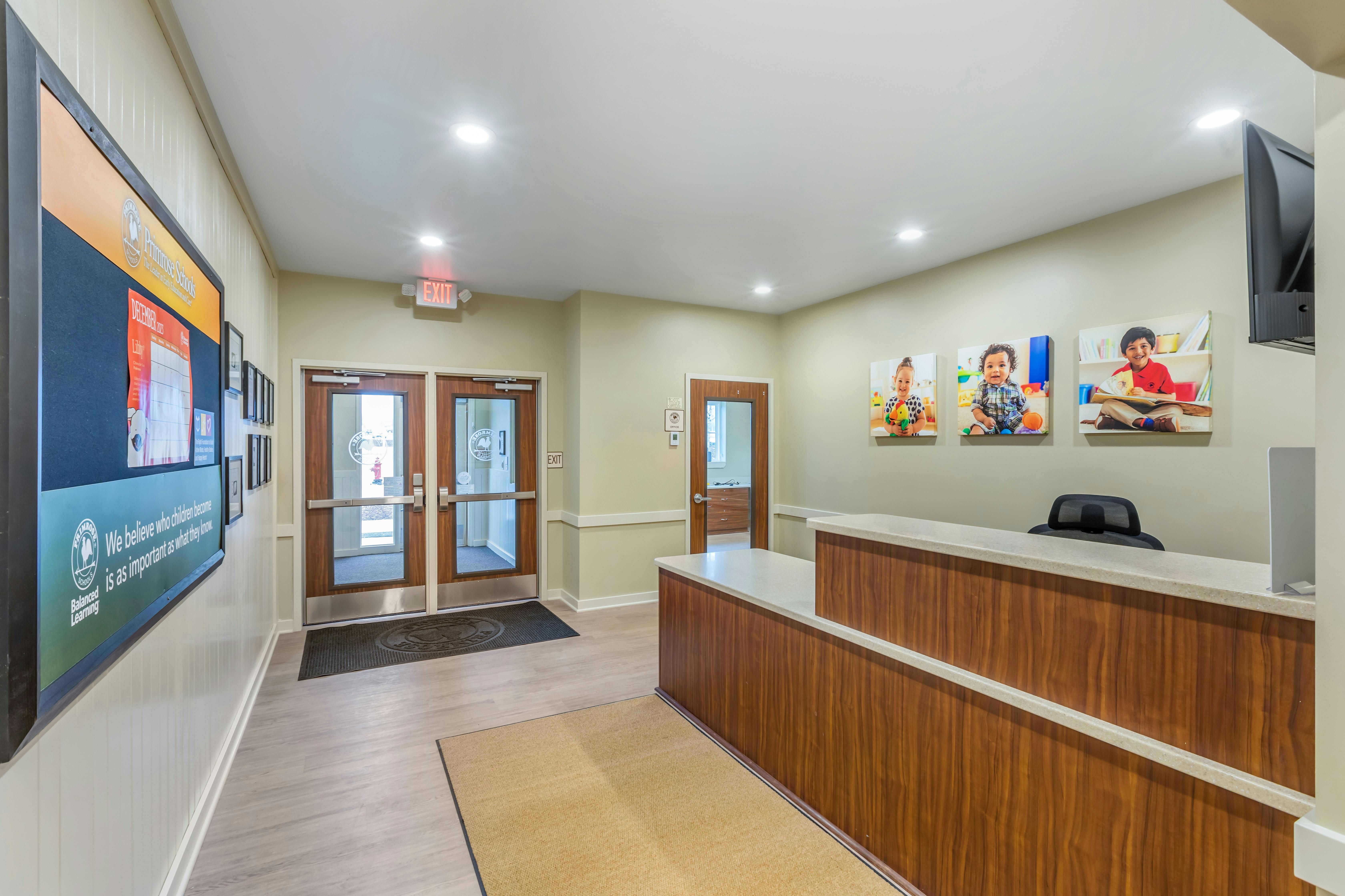 Reception area with a wooden desk, bulletin board, and photos of children