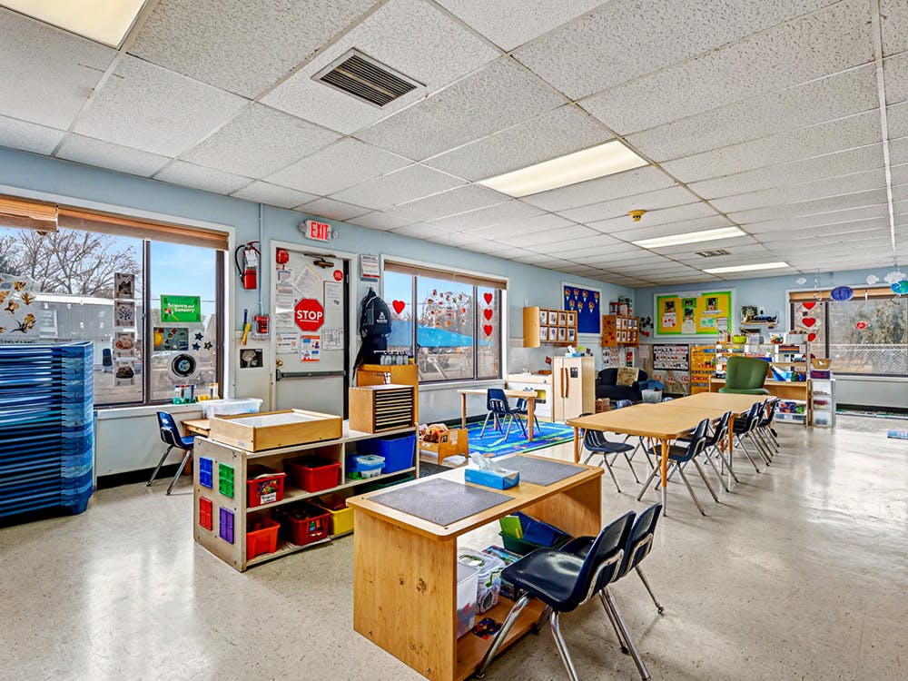 Empty classroom with light blue walls and tables with chairs