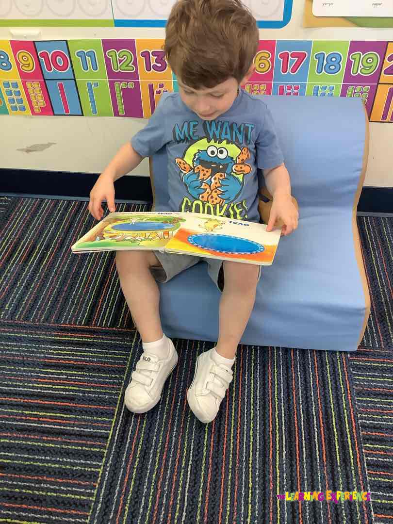 Child sitting on a blue chair reading a book