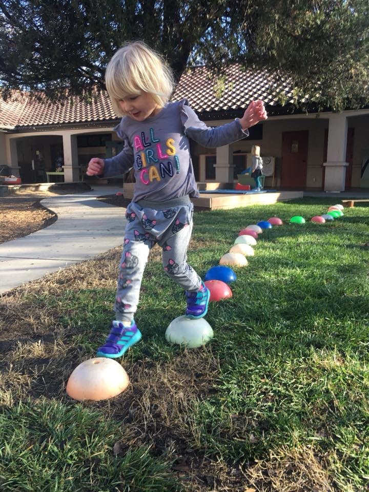 Child walking on colorful dome-shaped balance pods on grass