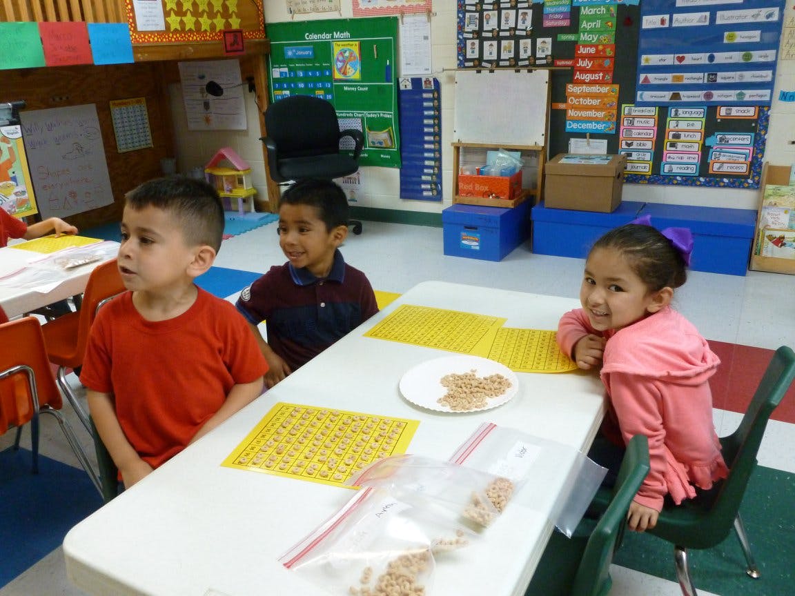 Three children sitting at a table in a classroom