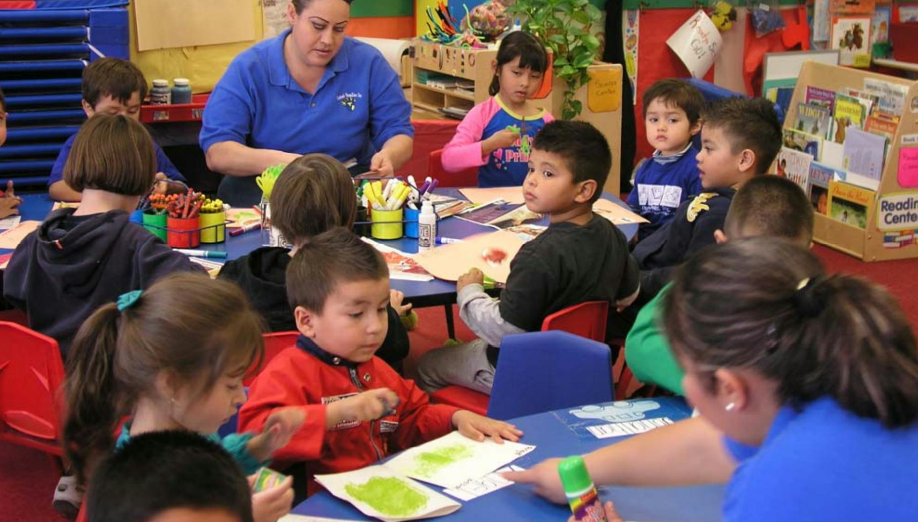 Adults and children seated at tables in a classroom