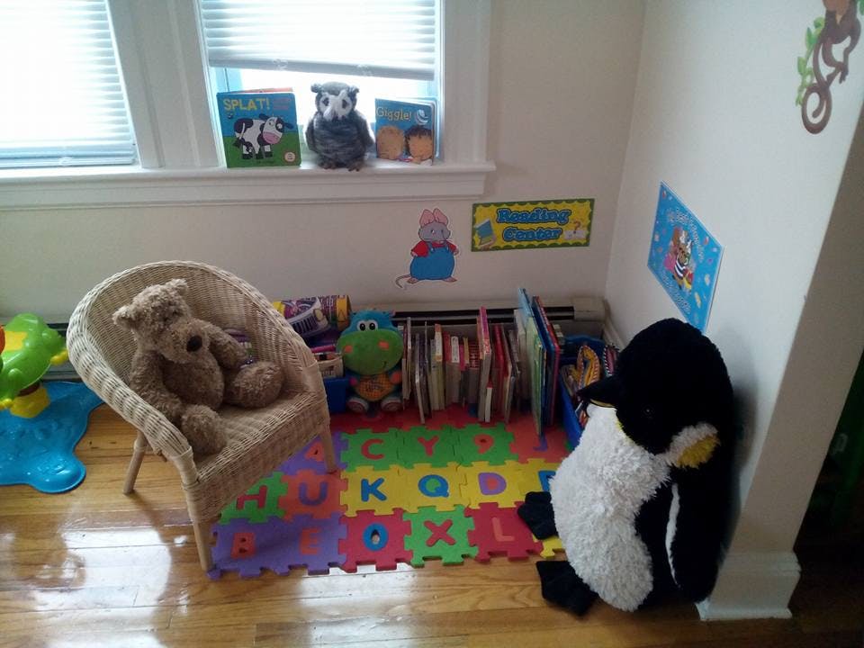 Child's room with a wicker chair, stuffed animals, books, and alphabet mat
