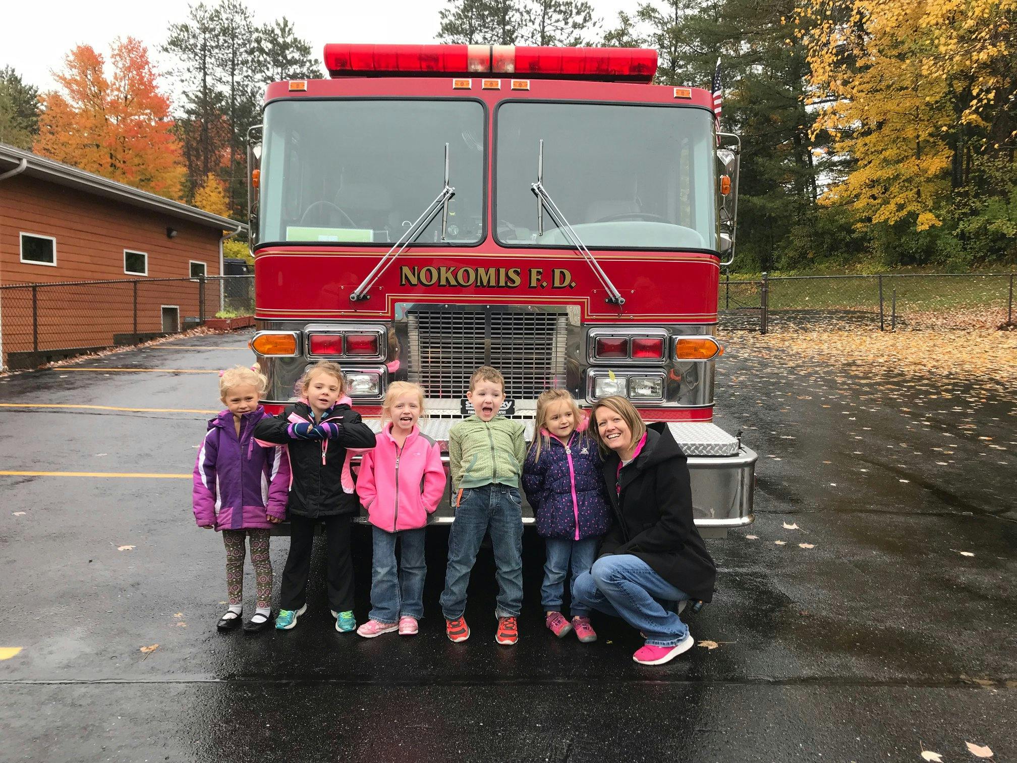 Adult and children posing in front of a fire truck with "Nokomis F.D." on it