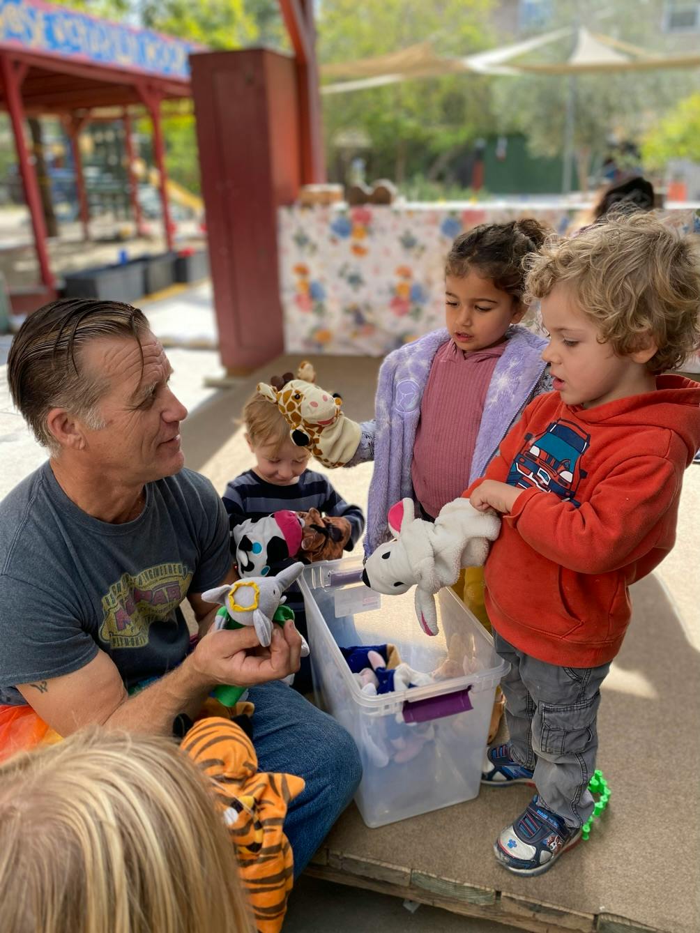 Adult and three children playing with puppet toys
