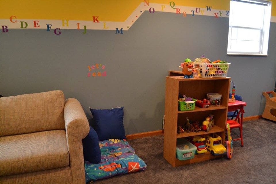 Playroom with a couch, floor mat, and toy shelf