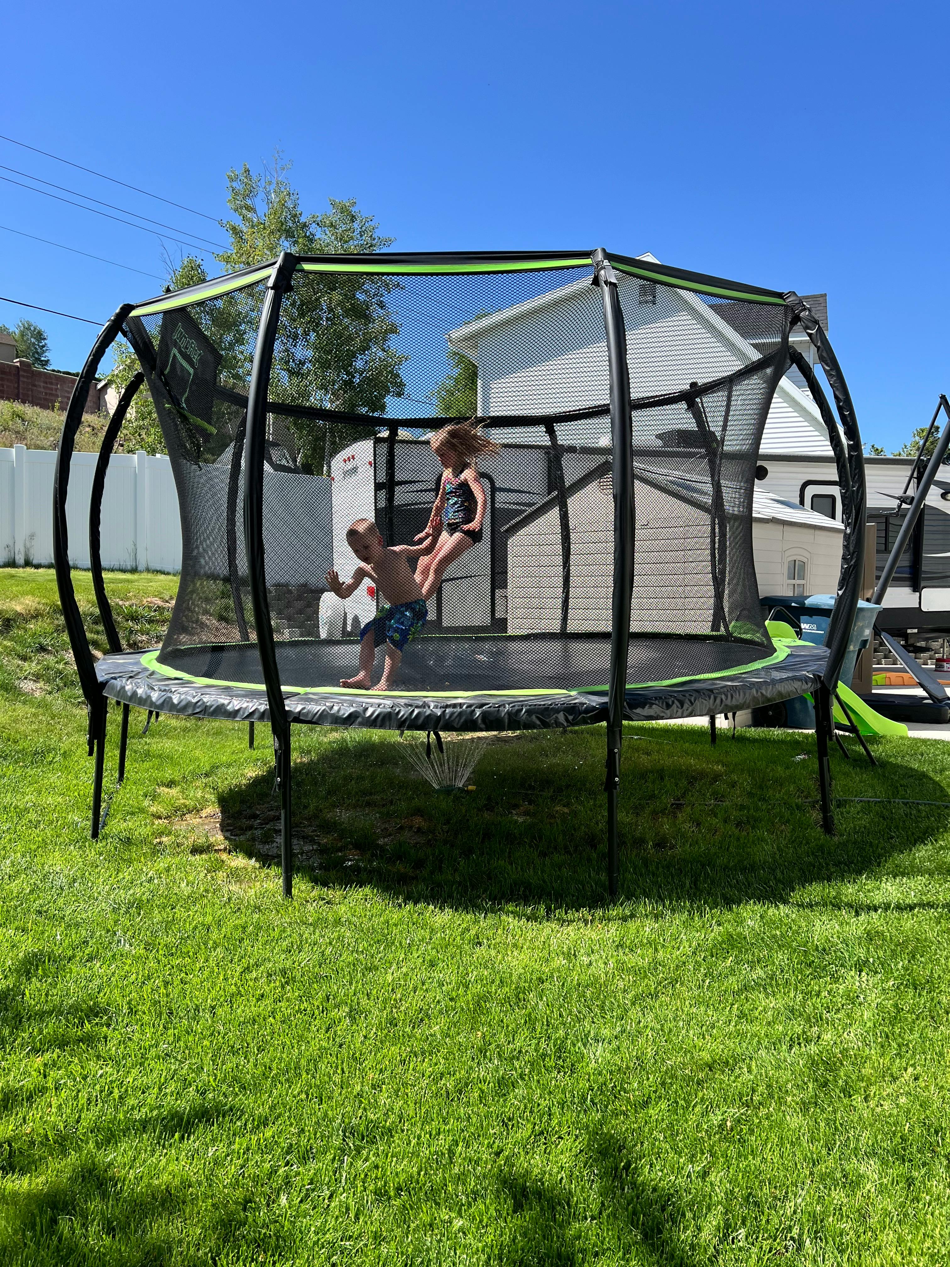 Two children jumping on a trampoline outdoors