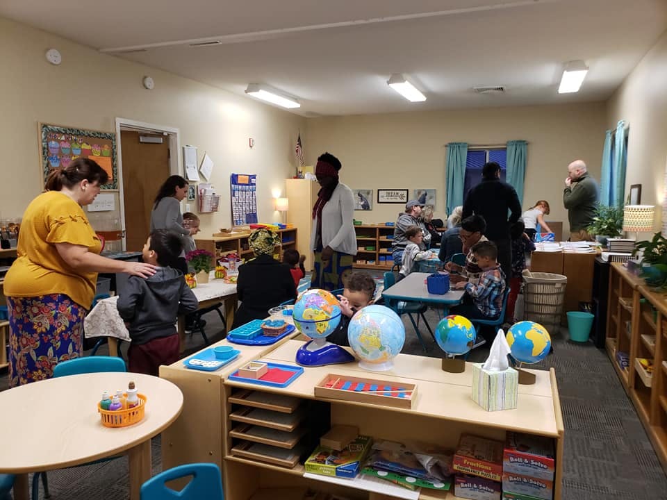 Adults and children in a classroom with globes on tables