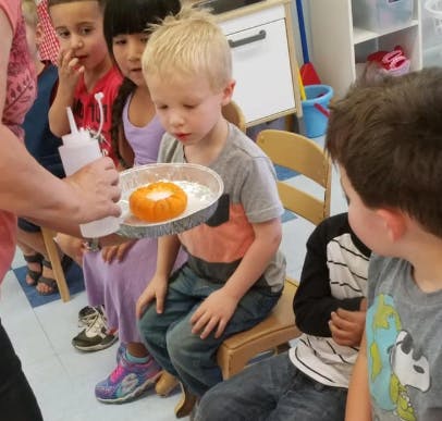 Person holding a squeeze bottle over a child's craft project
